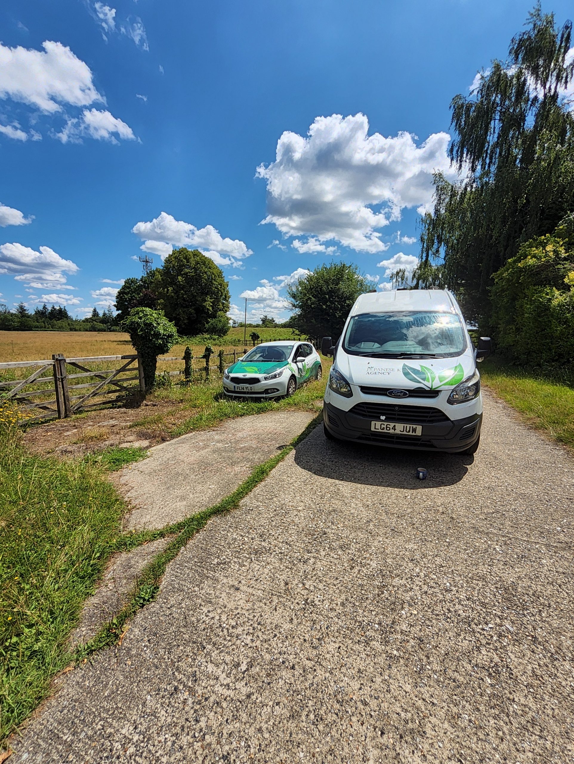 Two JKWA branded vans parked on a gravel track beside a grassy verge and field at an operational water infrastructure site in South East England